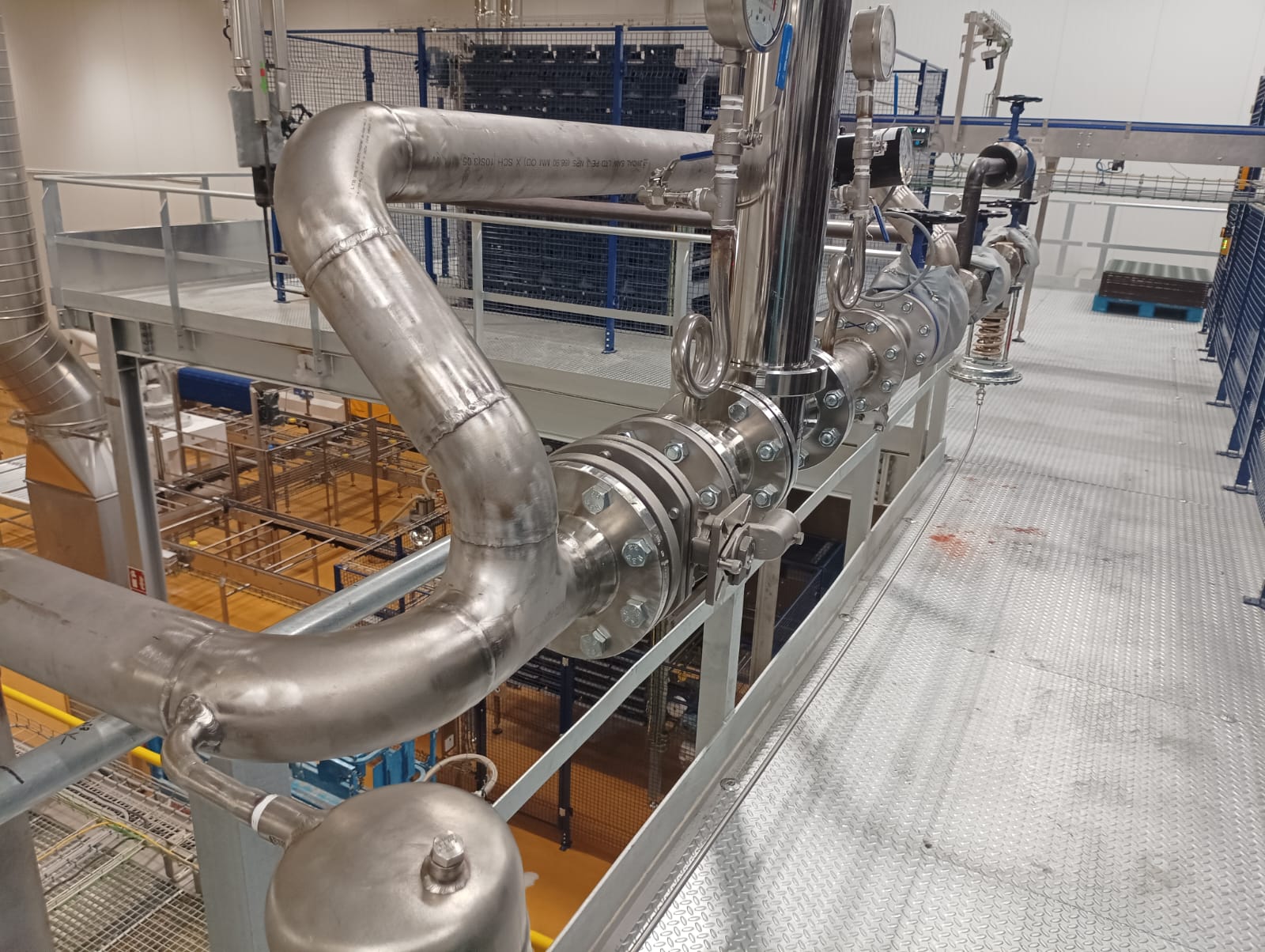 Red de tubería inoxidable con bridas y valvulería sobre pasarela técnica