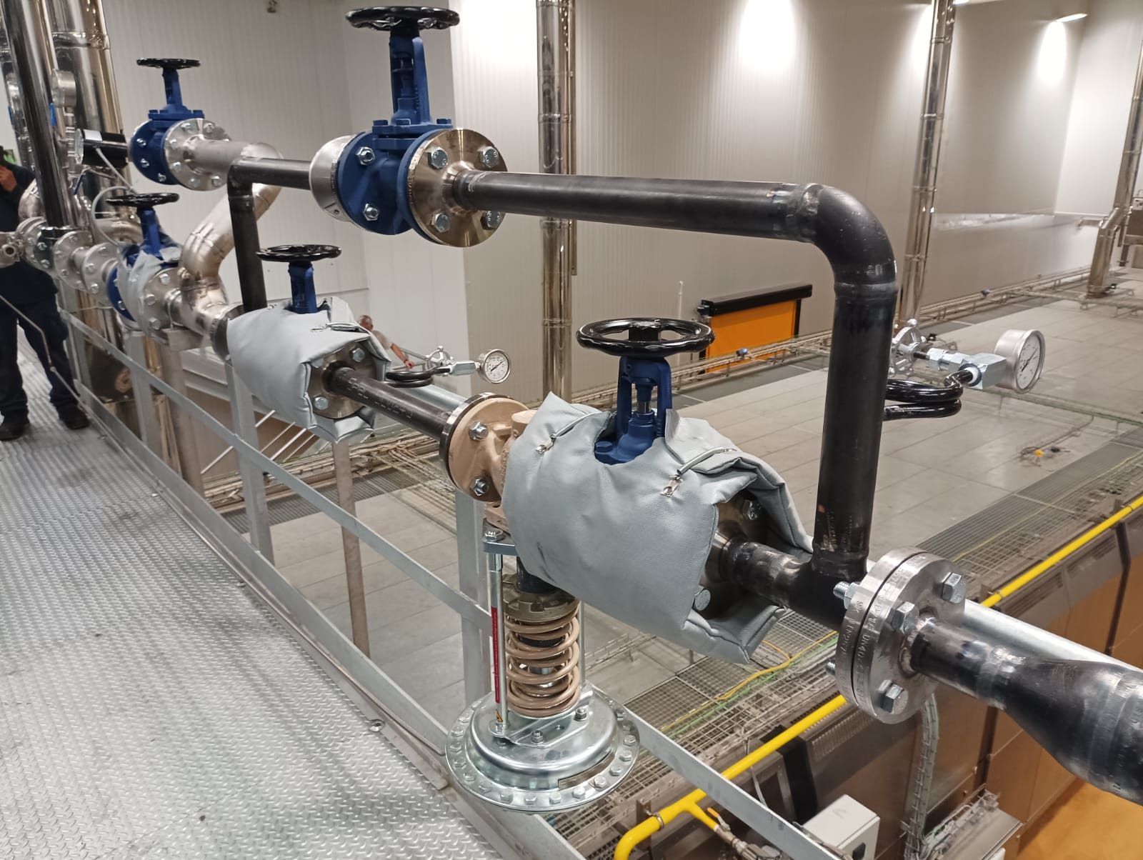 Tubería industrial con válvulas y aislamiento en sala técnica