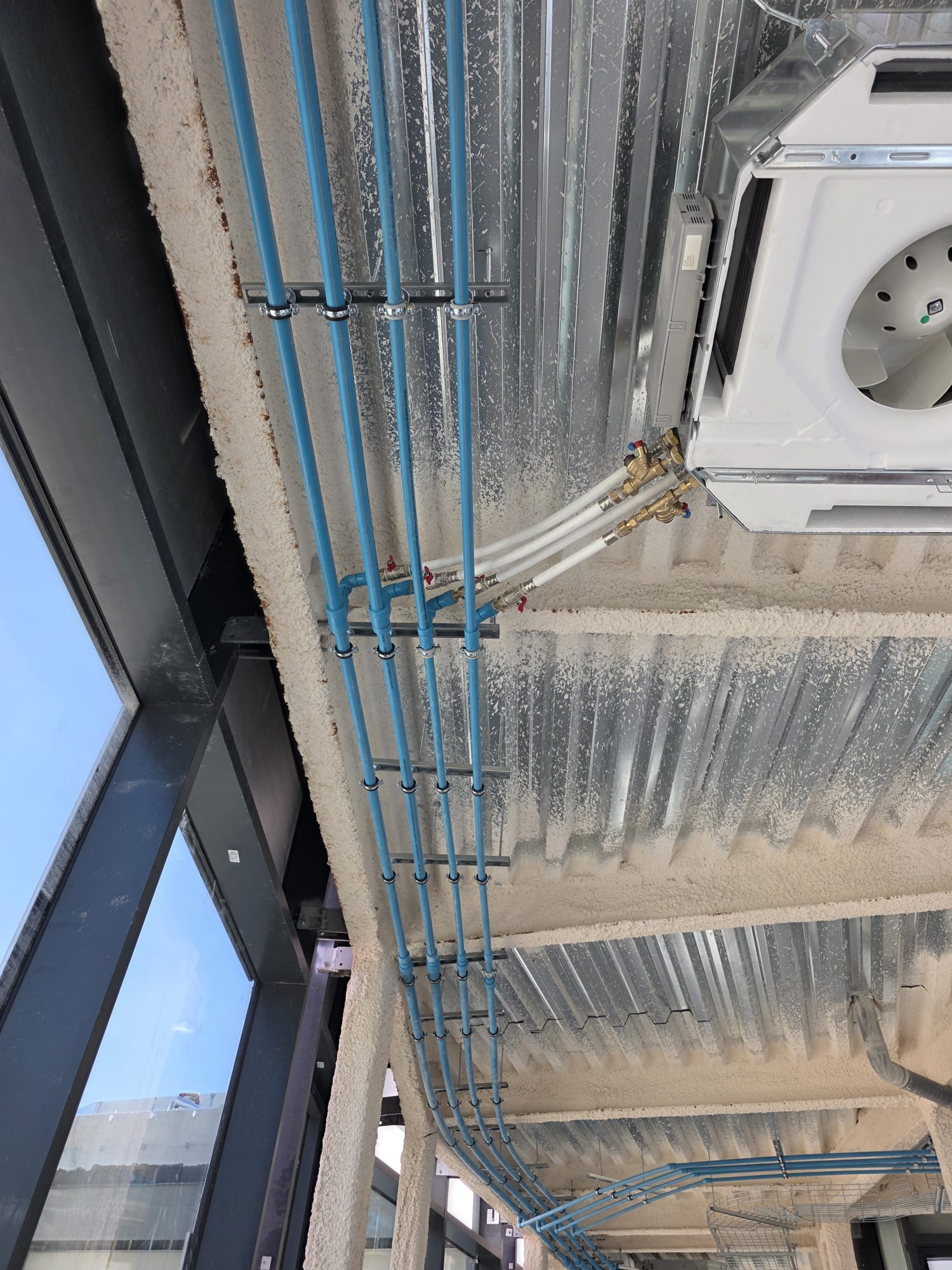 Equipo de climatización integrado junto a tuberías azules
